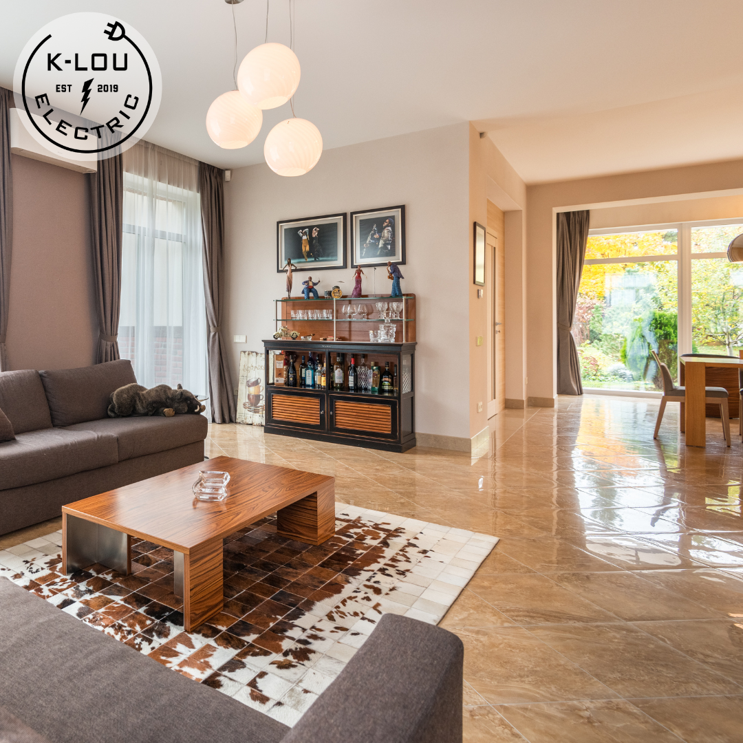 Modern living room with marble floors, brown sectional sofa, wooden coffee table, and decorative bar cabinet, featuring globe pendant lights and large windows with gray curtains