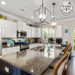 Modern kitchen interior with granite countertops, pendant lighting, and a dining area featuring white cabinets and stainless steel appliances